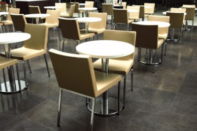 無人の社食のような共有スペースに並ぶテーブルと椅子